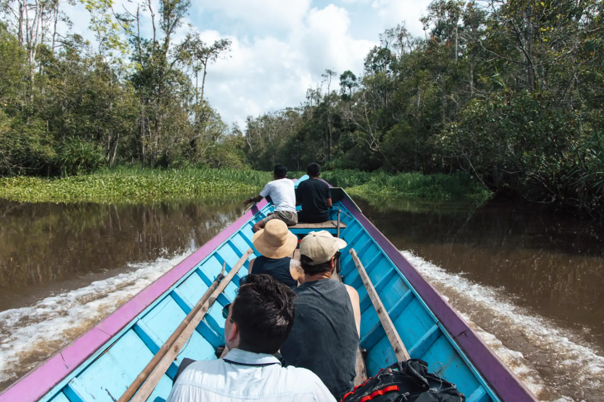 Group navigating the river in a colourful boat through the Borneo jungle